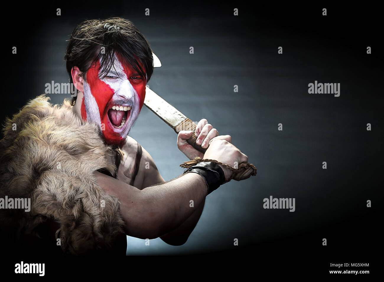 Portrait of man in war paint, with an ax in his hands, a warrior  brandishing an ax furiously screaming, barbarian of ancient times, Viking  and savage Stock Photo - Alamy
