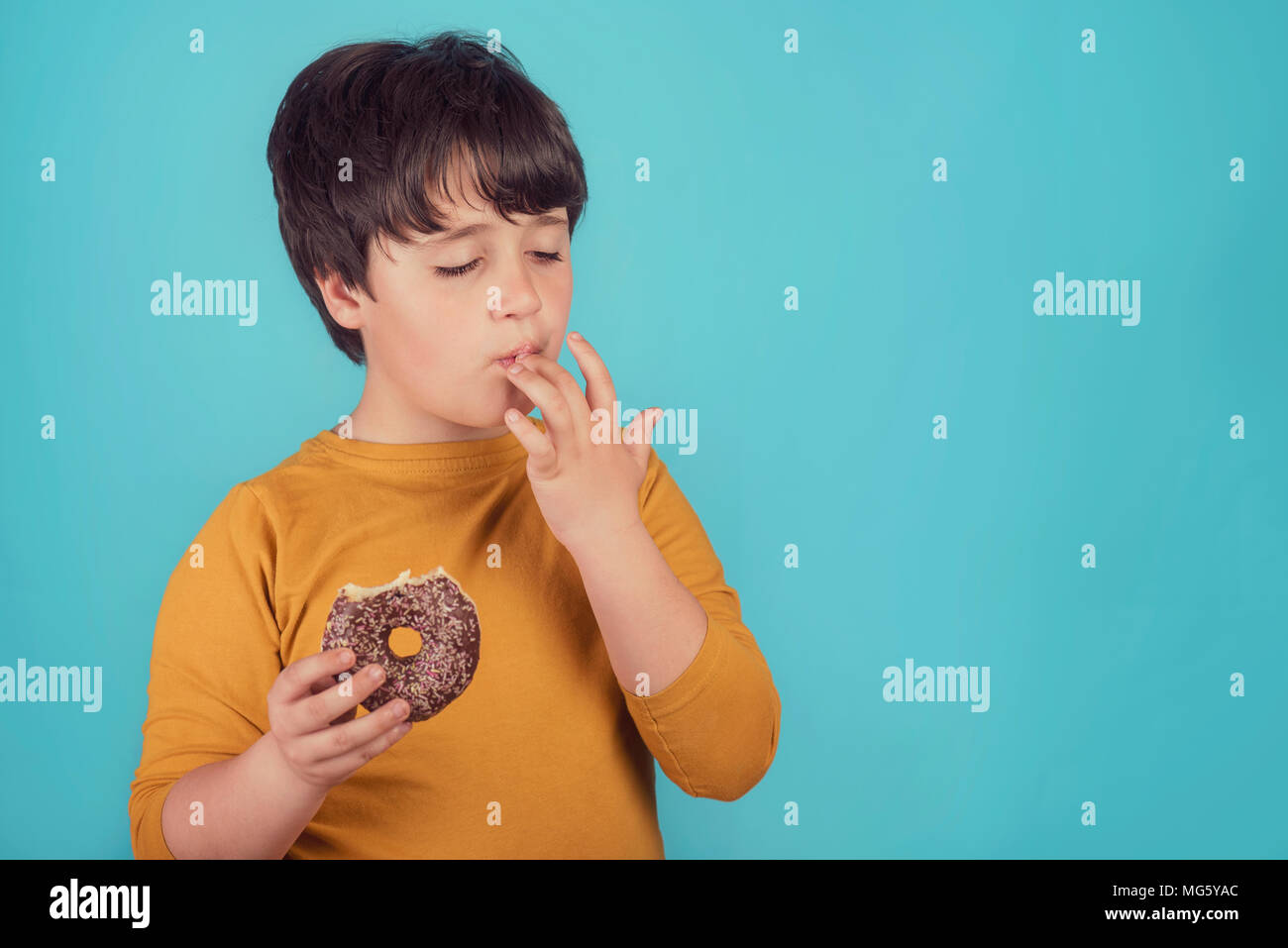 boy eating donut on blue background Stock Photo