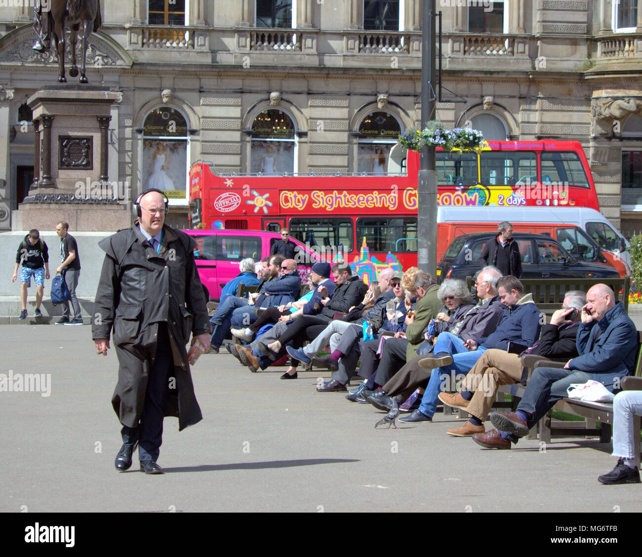 Glasgow, Scotland, UK 27th April. UK Weather old man with headphones oap : city sightseeing Glasgow bus with tourists Sunshine comes to the city as the locals and tourists enjoy the hot weather in George Square at the heart of the city. Gerard Ferry/Alamy news Stock Photo