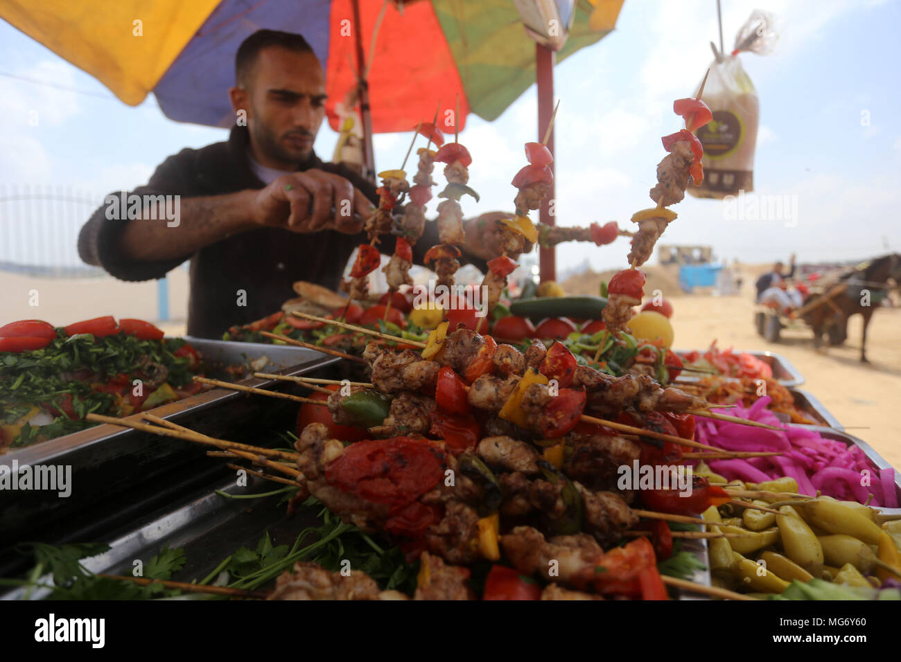 Bureij, Gaza Strip, Palestinian Territory. 27th Apr, 2018. A Palestinian man prepares chicken Grill during clashes with Israeli security forces during tents protest demanding the right to return to their homeland, in Bureij in the cetner of Gaza strip on April 27, 2018 Credit: Yasser Qudih/APA Images/ZUMA Wire/Alamy Live News Stock Photo