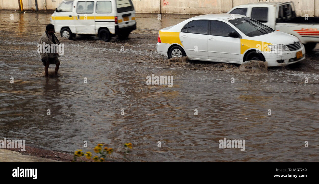 Sanaa, Yemen. 27th Apr, 2018. A man walks through a flooded street