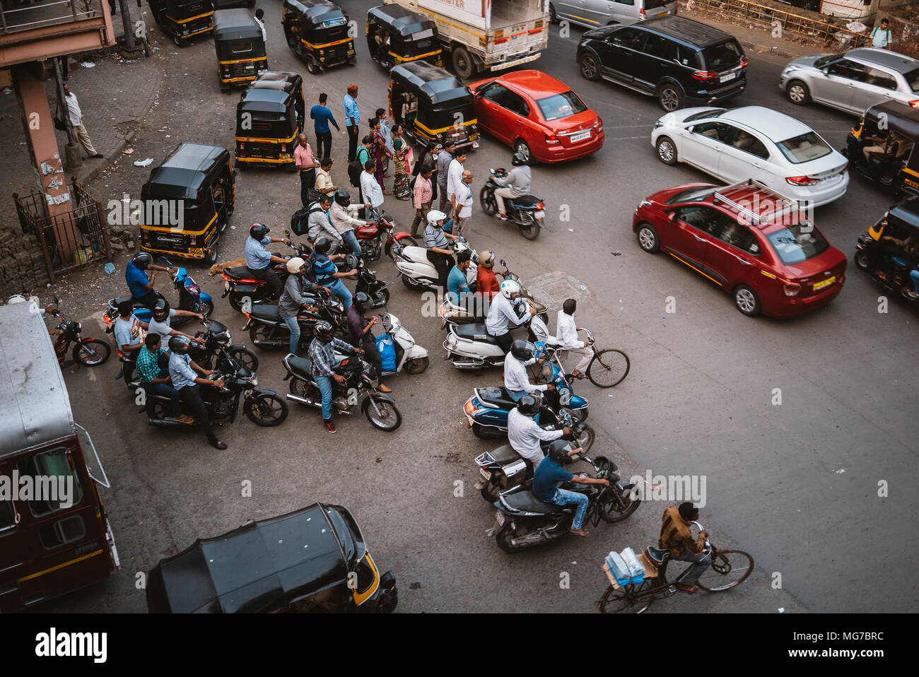 a group of Indian men on scooters waiting to turn at a busy intersection in Goa, India Stock Photo