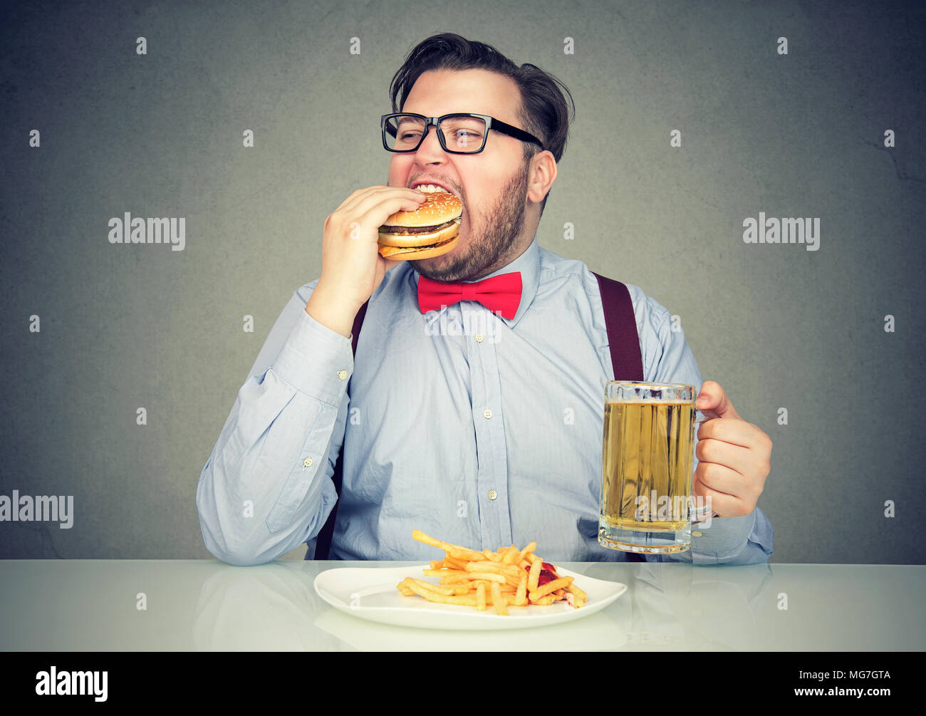 Business man eating junk food drinking beer Stock Photo