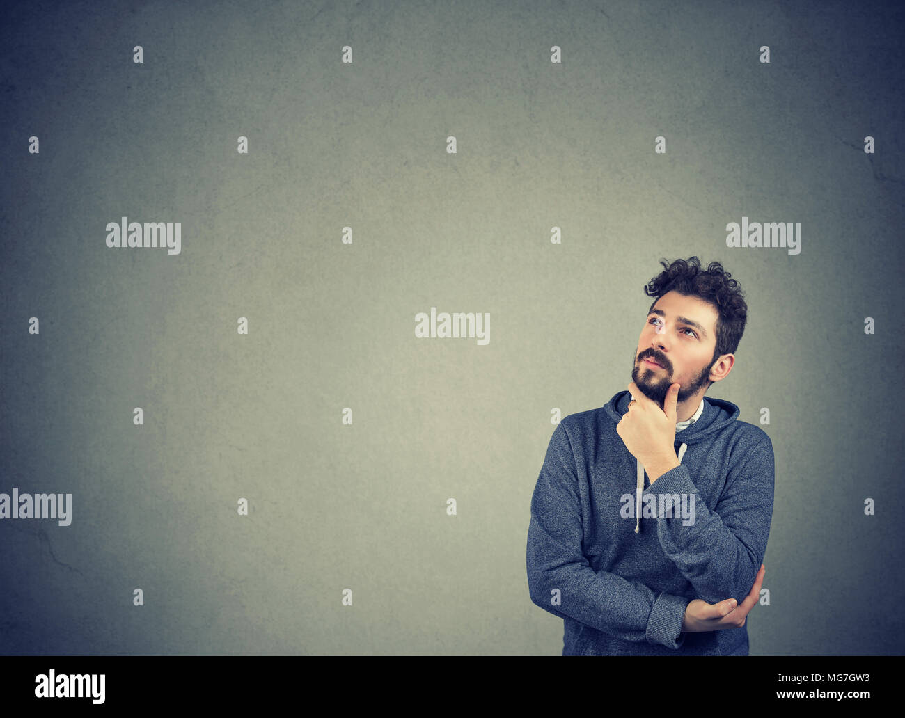 Portrait of a serious man thinking looking up isolated on wall background with copy space. Human emotions, perception Stock Photo