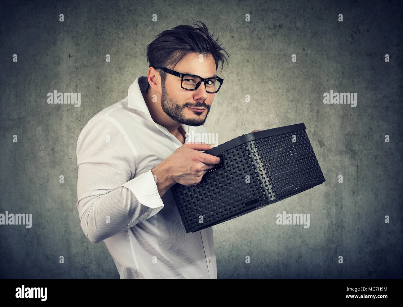 Unsociable man holding a box and looking unwilling to share while posing on gray. Stock Photo