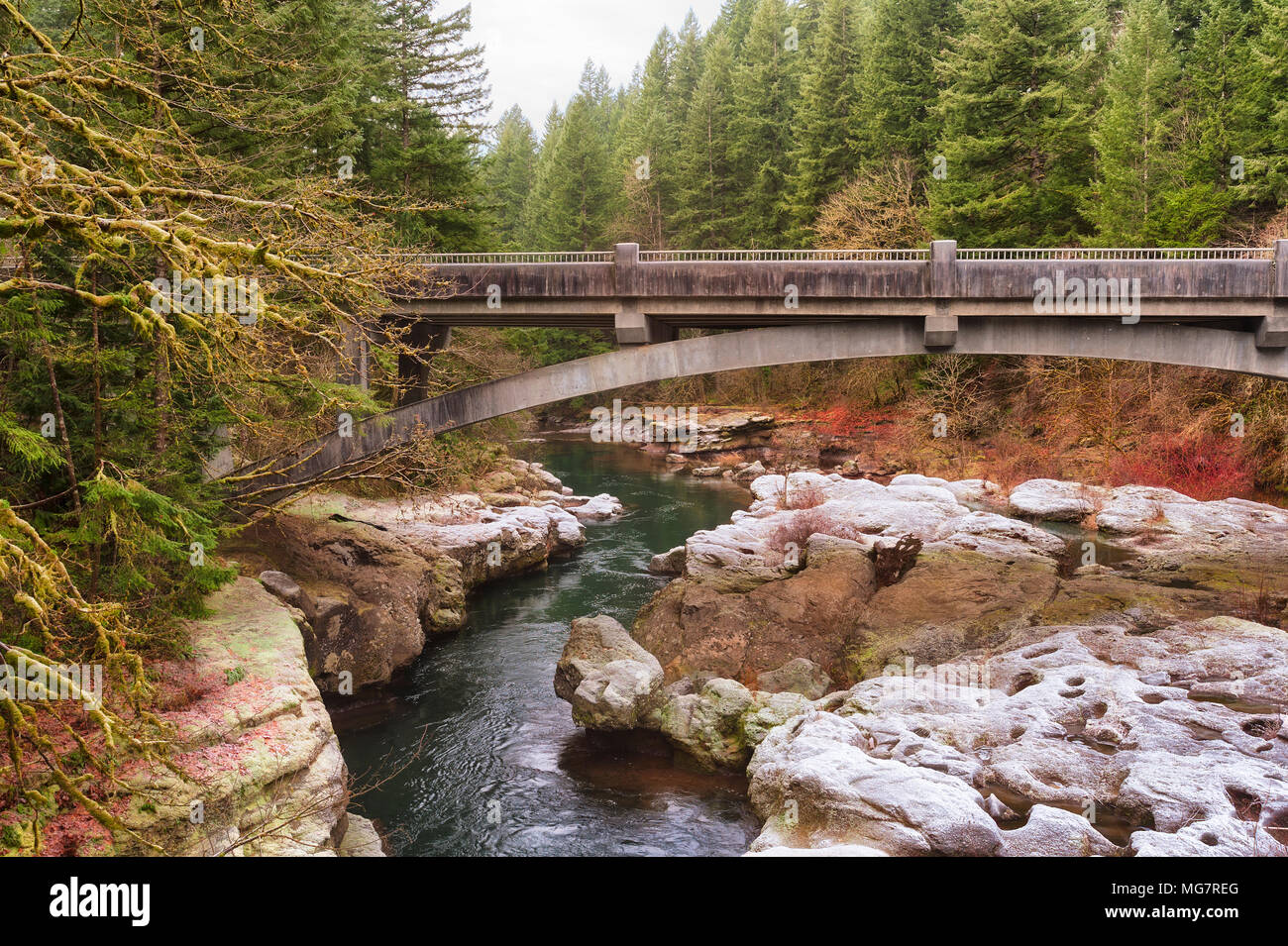 A bridge crosses the East Fork of the Lewis River in Clark County, Washington, with a light dusting of snow on a frosty winter morning in this serene  Stock Photo