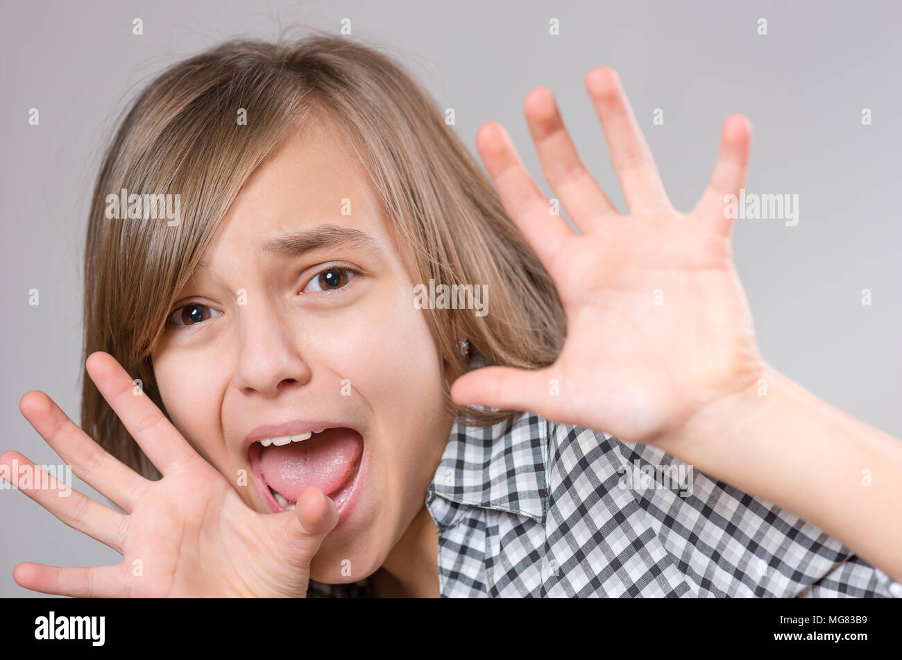 Emotional portrait of excited little girl. Funny cute surprised child 10 year old with mouth open in amazement. Shocked teenager with hands near the h Stock Photo