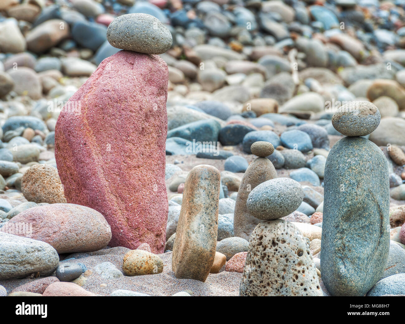 Stacks of river rocks resembling people along a sandy beach of the Sandy River in Oregon.  Many are grouped into little families, solidarity figures t Stock Photo
