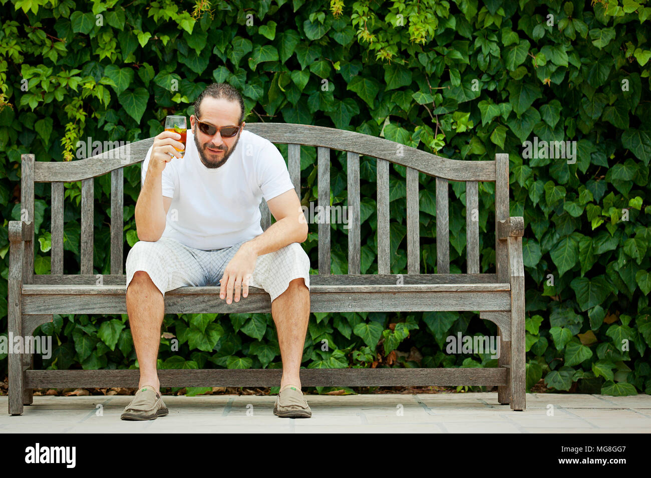 Portrait shoot outdoors of man sitting on wooden bench Stock Photo