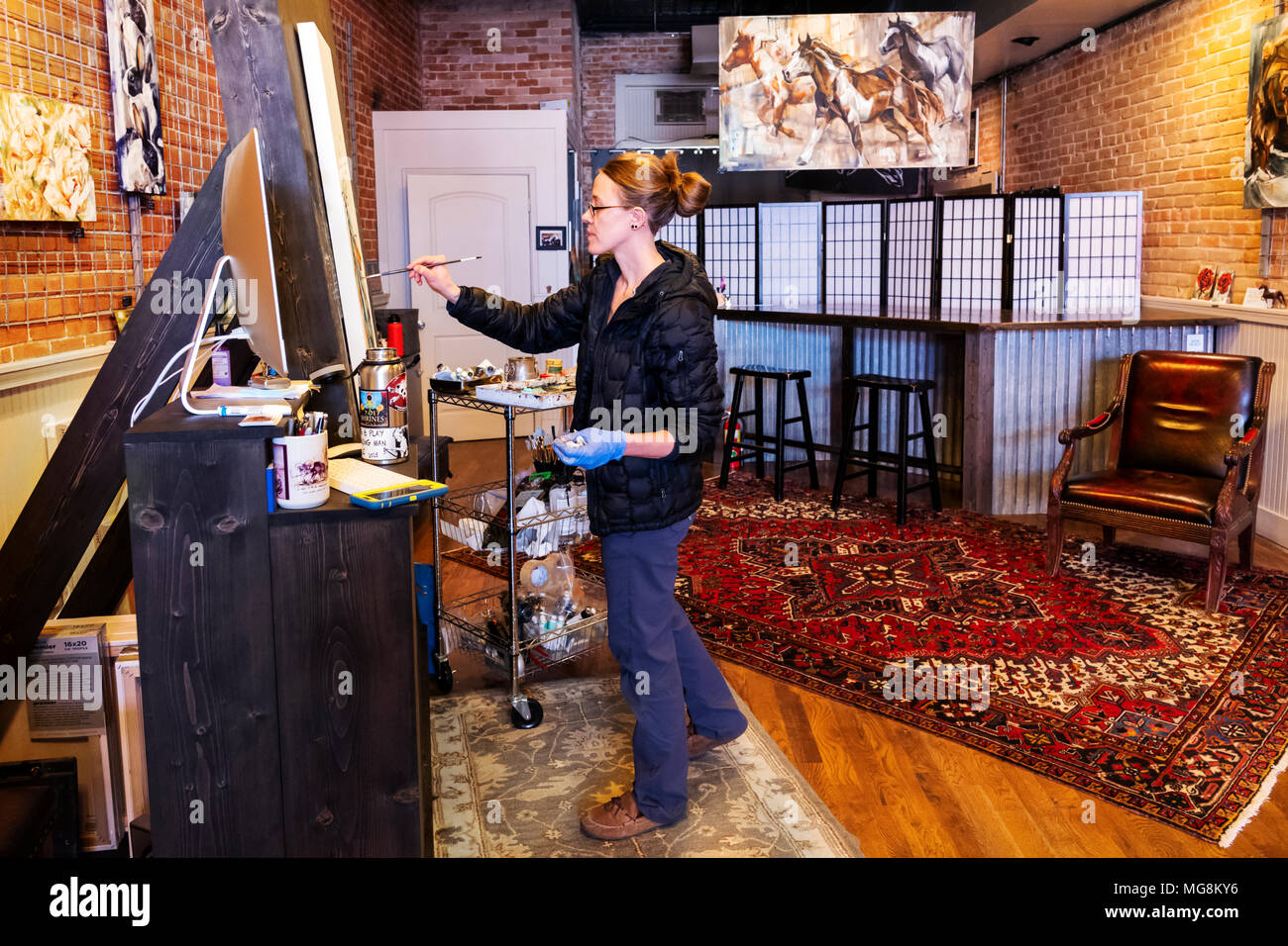 Fine artist Katie Maher creating an oil painting in her gallery; Salida; Colorado; USA Stock Photo