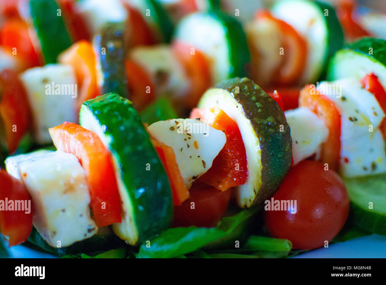 Halloumi, courgette, red pepper kebabs served on a salad bed, a healthy vegetarian meal. Stock Photo