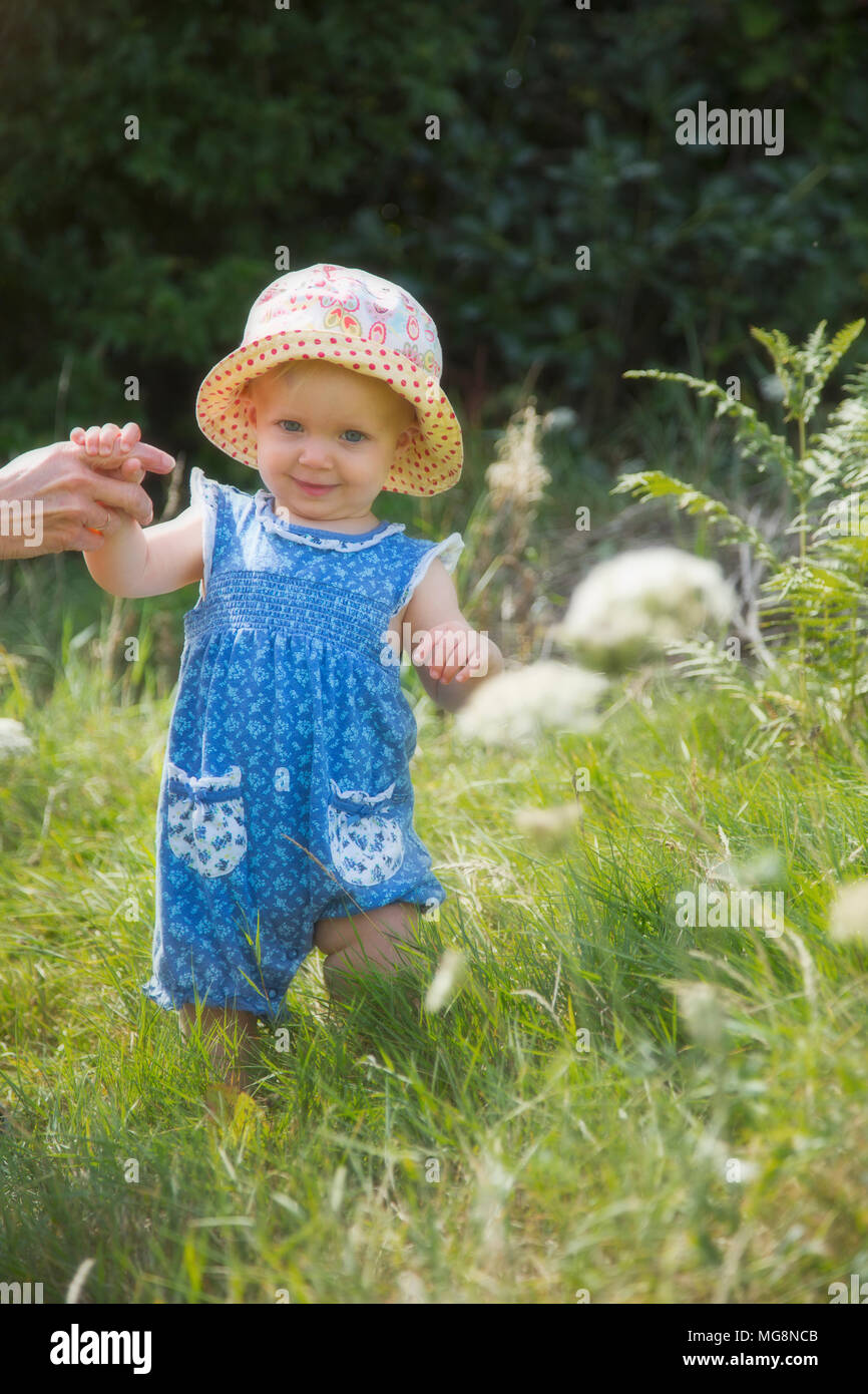 A sweet little baby girl learning to walk in summer Stock Photo