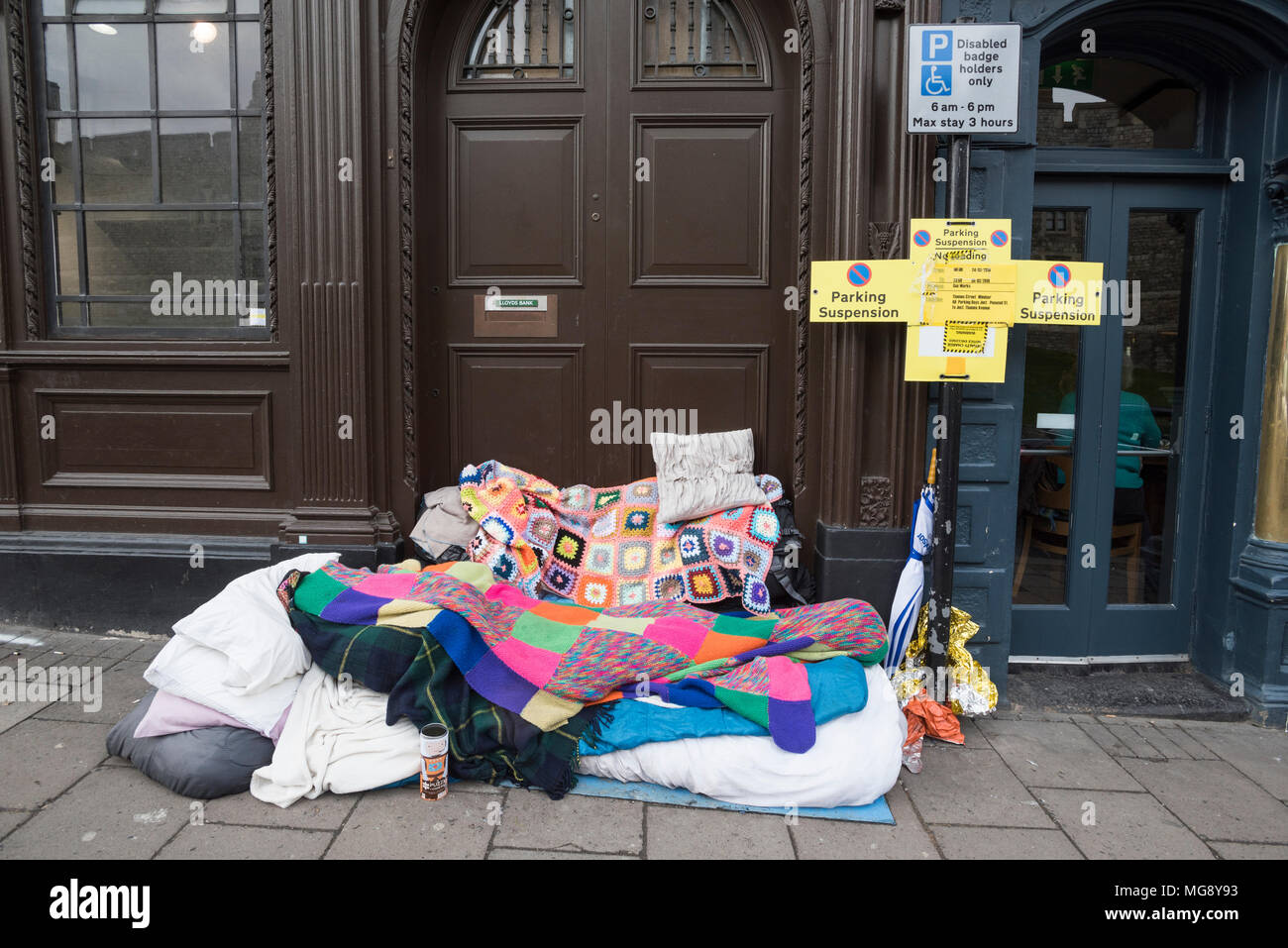 Bedding of a rough sleeper, just opposite Windsor Castle, Windsor, UK. The reflection of the Castle is visible in the window on the left. Stock Photo