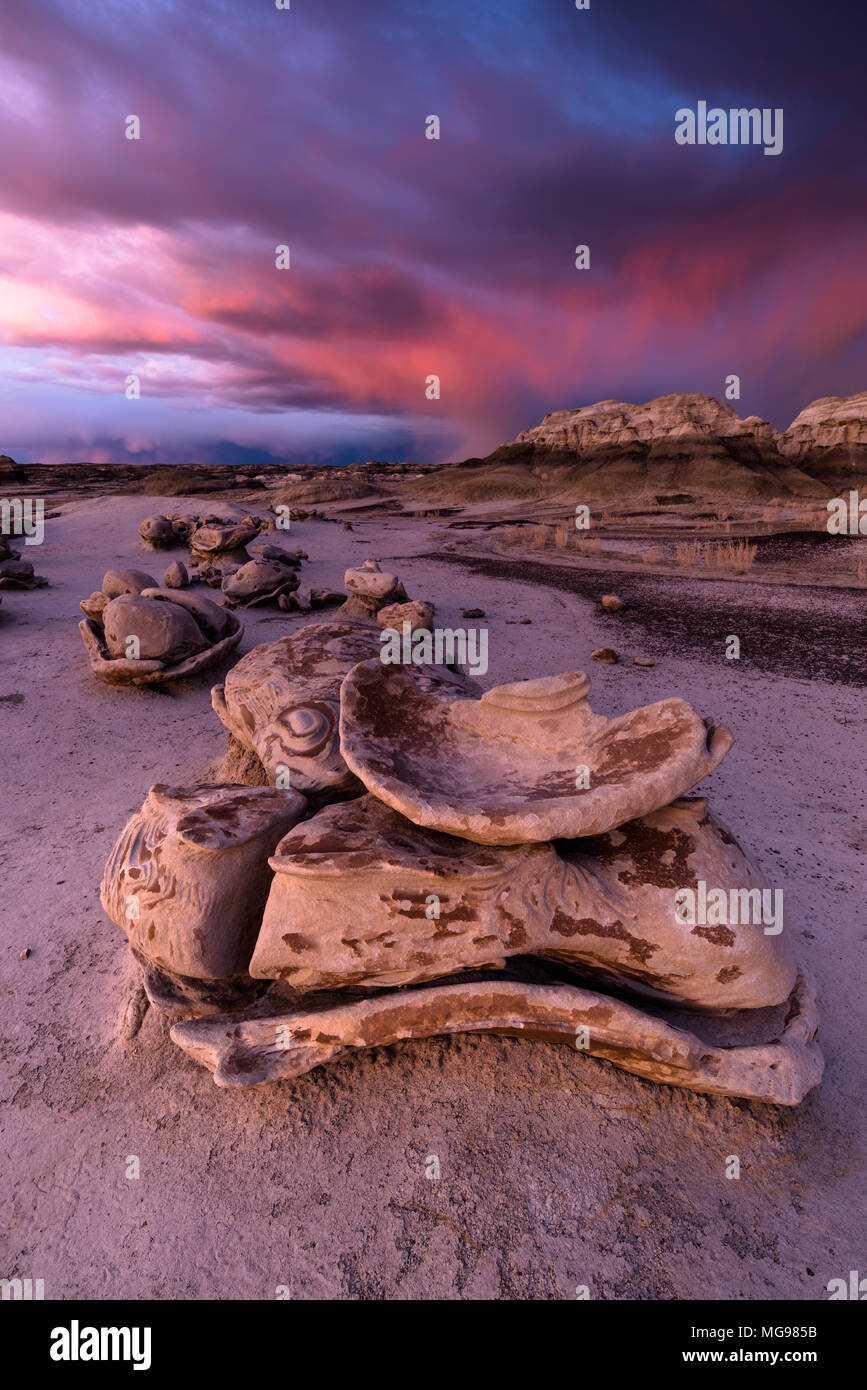 Bisti or De-Na-Zin Wilderness Area or badlands rock formations at sunset with storm clouds in background, New Mexico, USA Stock Photo