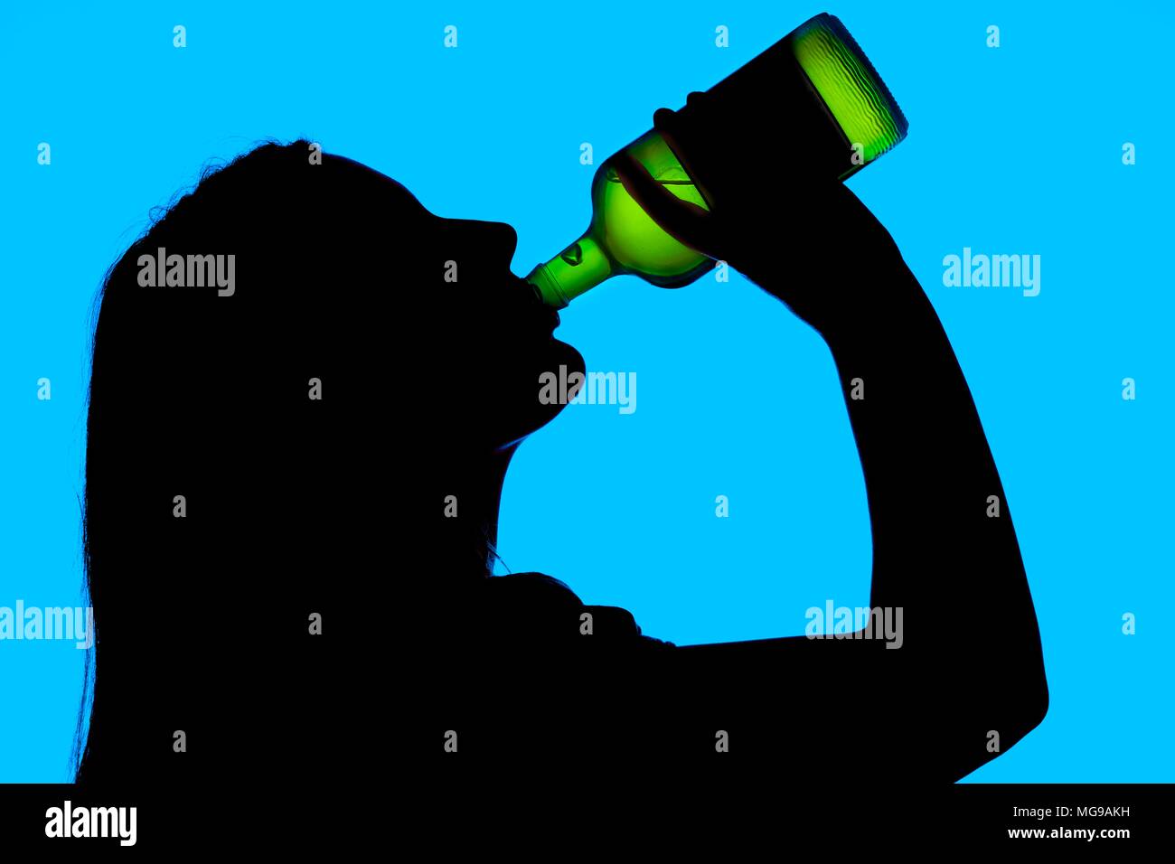 Woman drinking straight from bottle, silhouette. Stock Photo