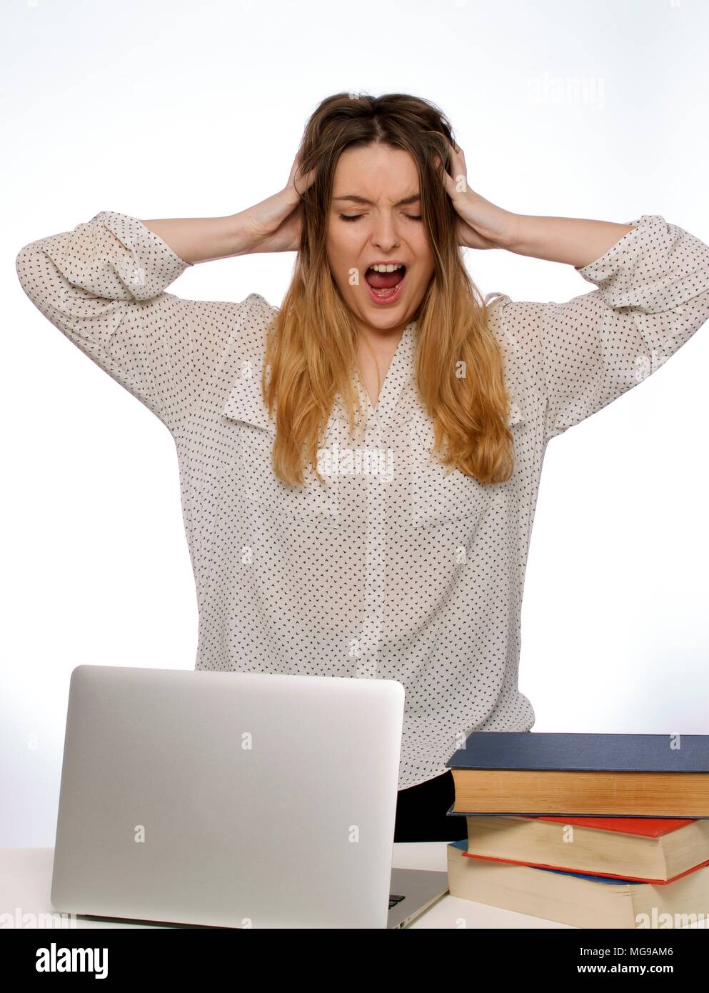 Young woman with hands in hair and laptop. Stock Photo