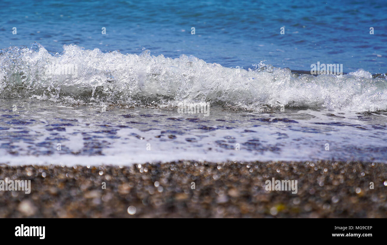 Selective focus of coastal sea, ocean crashing wave with foam splashes on its top Stock Photo