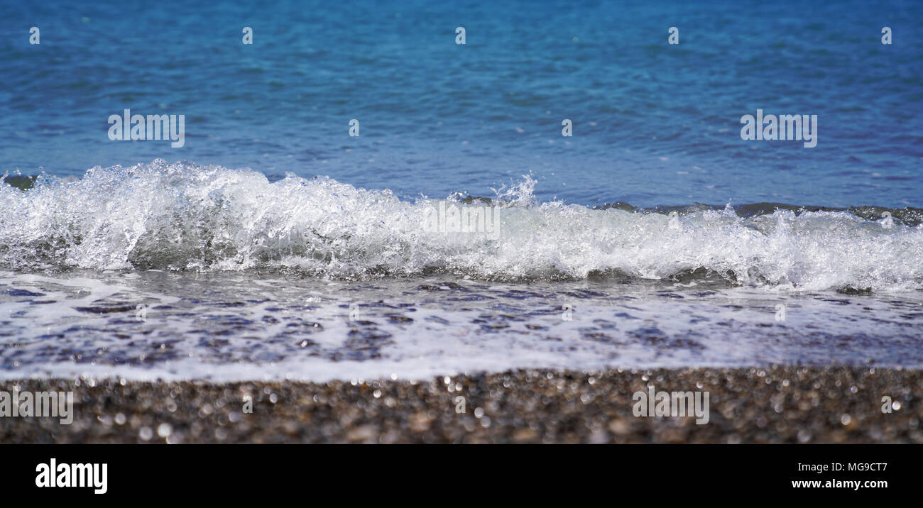 Selective focus of coastal sea, ocean crashing wave with foam splashes on its top Stock Photo