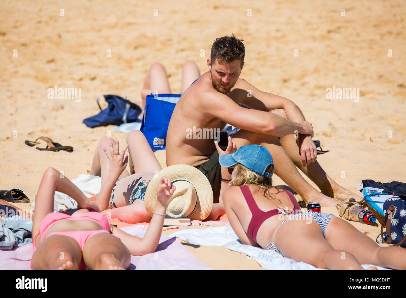 Young people, one man and three women relax together ona Sydney beach,Australia Stock Photo