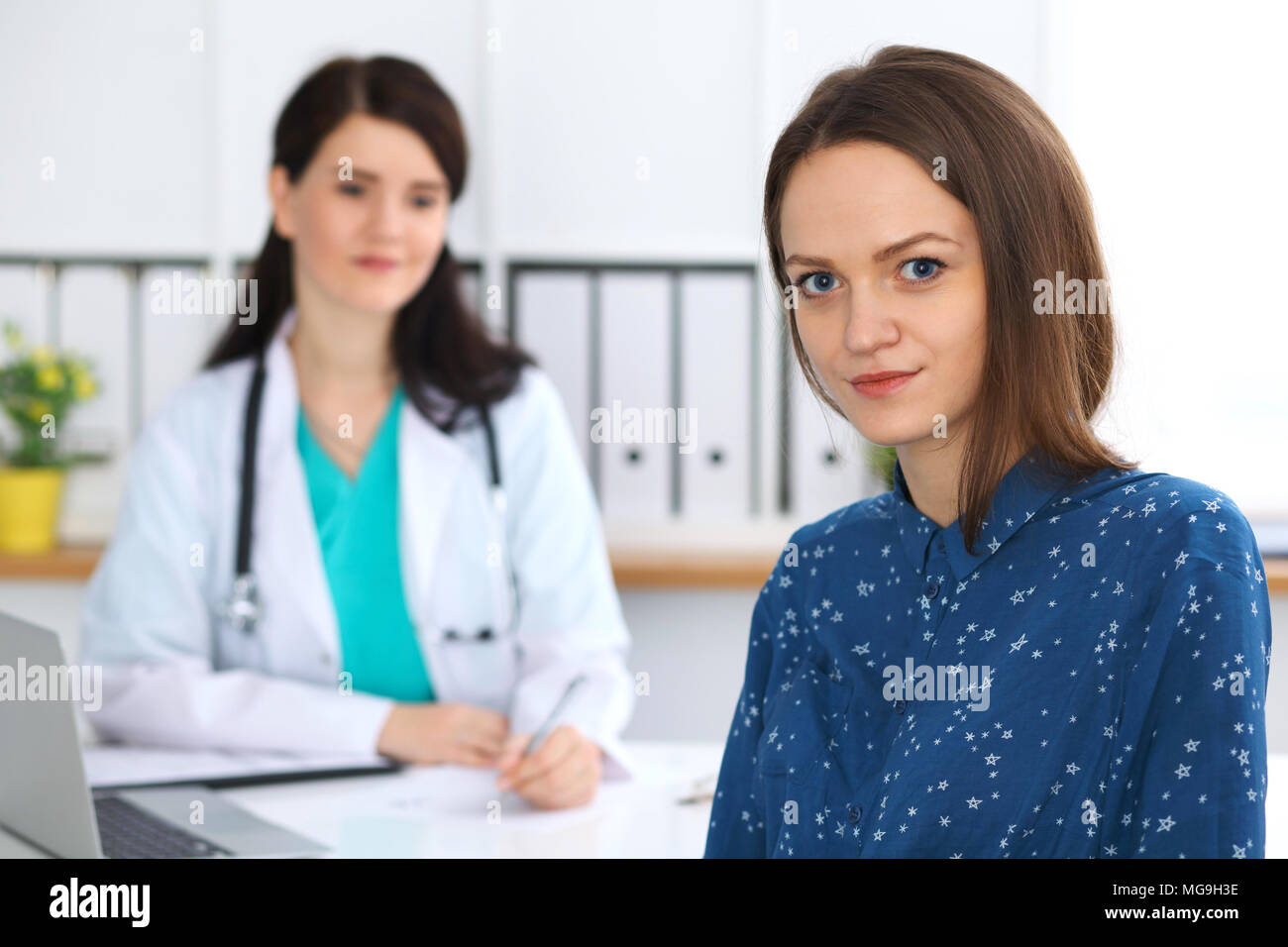 Doctor and patient having a talk while sitting at the desk. Focus on ...