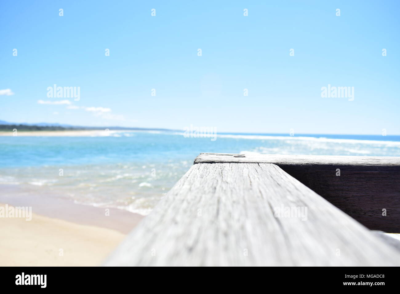 Australian beach with railing on pier on the foreground. Low depth of field, light mood. Stock Photo