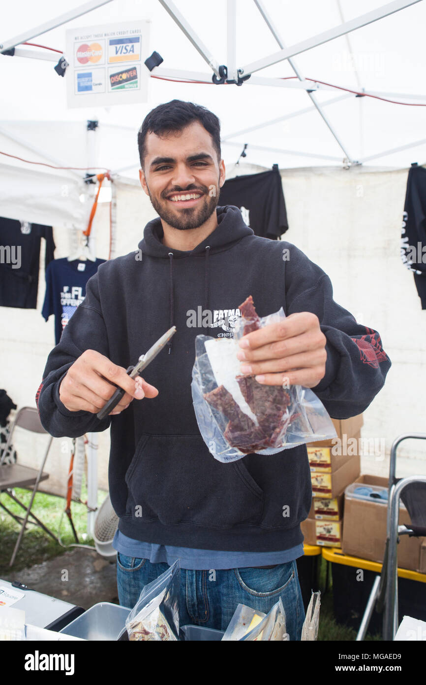 Portrait of a vendor offering a sample of his homemade beef jerky at a food fair Stock Photo