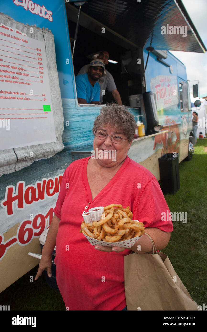 Tortured of an overweight customer at a food truck with a basket full of fried food Stock Photo