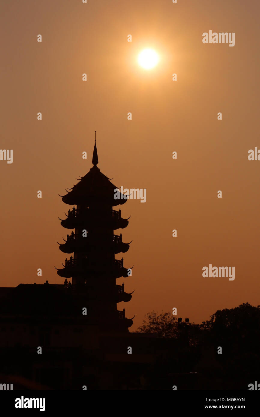 Silhouette of a traditional pagoda building against an orange sunset, Bangkok, Thailand. Stock Photo