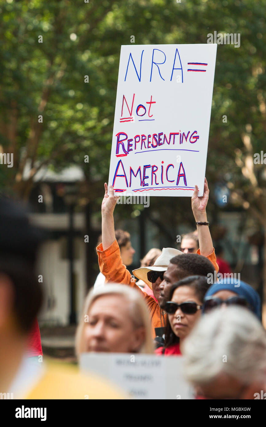 A woman holds up a sign that says "NRA = Not Representing America" at a Moms Demand Action anti-gun rally on April 29, 2017 in Atlanta, GA. Stock Photo