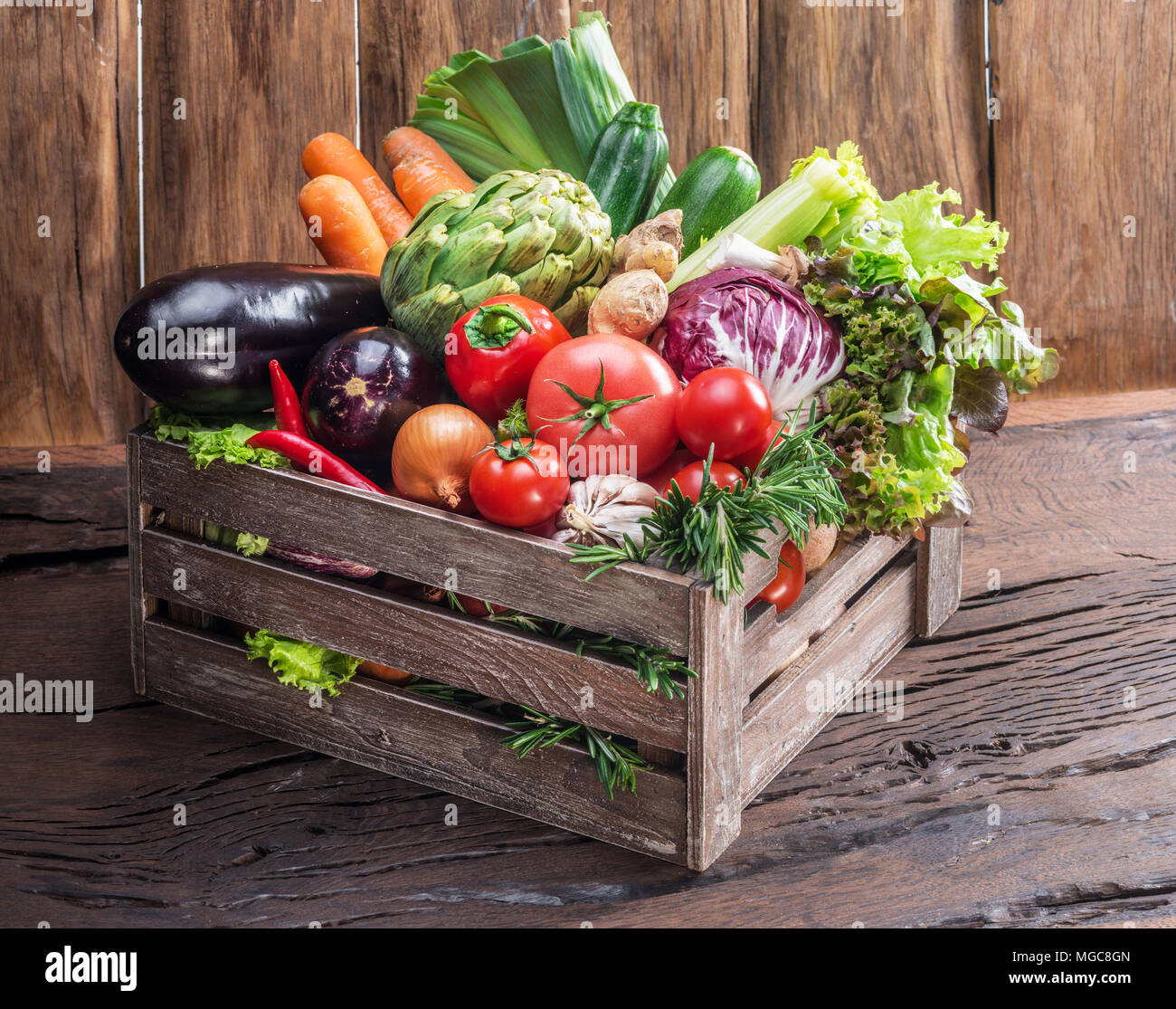 Fresh multi-colored vegetables in wooden crate. Wooden background. Stock Photo