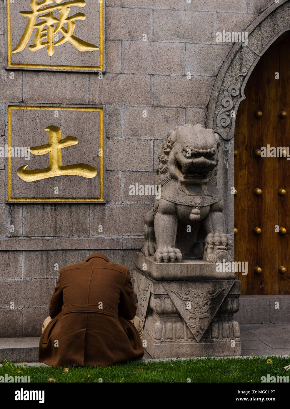 Man sitting with his head in his hands in front of a temple, rear view,  Shanghai, China Stock Photo