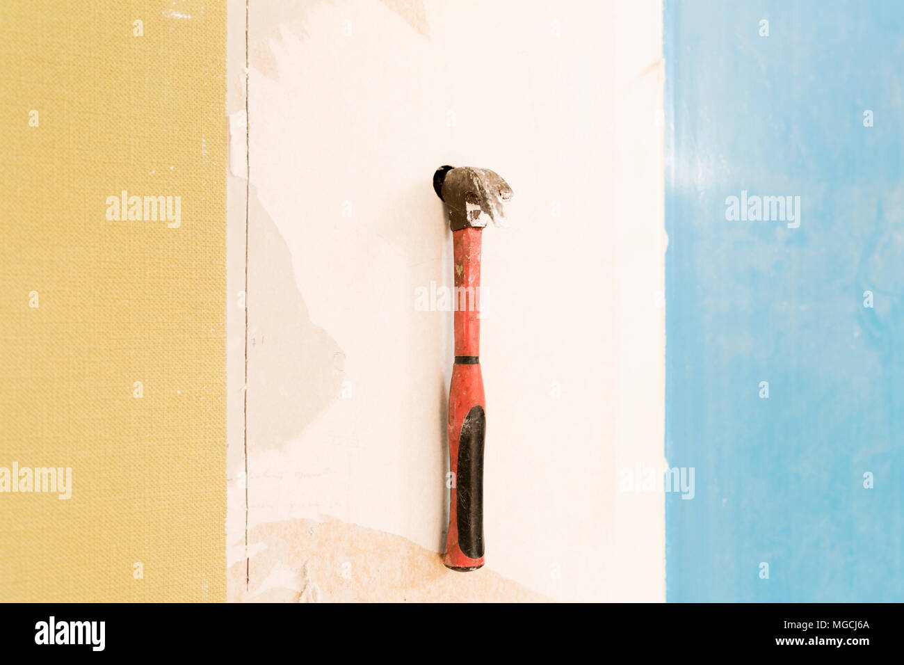 Builder hitting a wall with a hammer. Home renovation concept. Break wall to make new Stock Photo