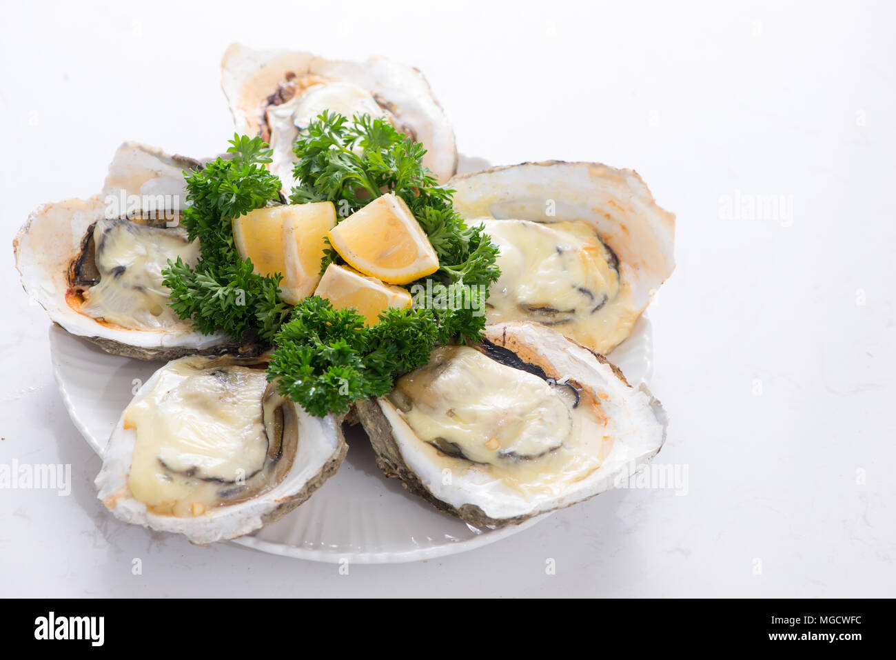 Opened oysters, ice and lemon on wooden board over stone table. Half dozen. With copy space Stock Photo