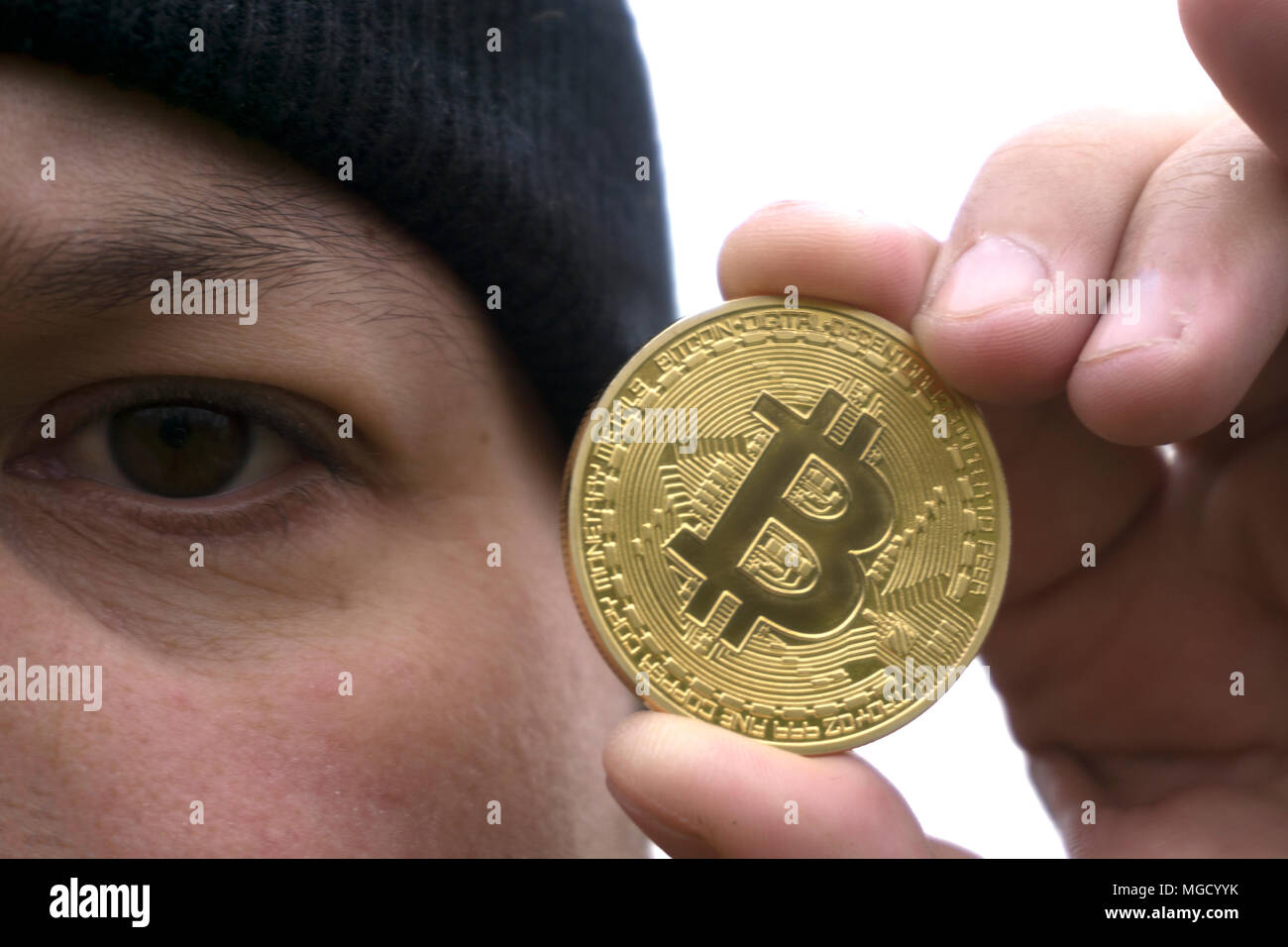 mad bitcoin lover with a gold coin in your hand , funny miner with BTC near  the face Stock Photo - Alamy