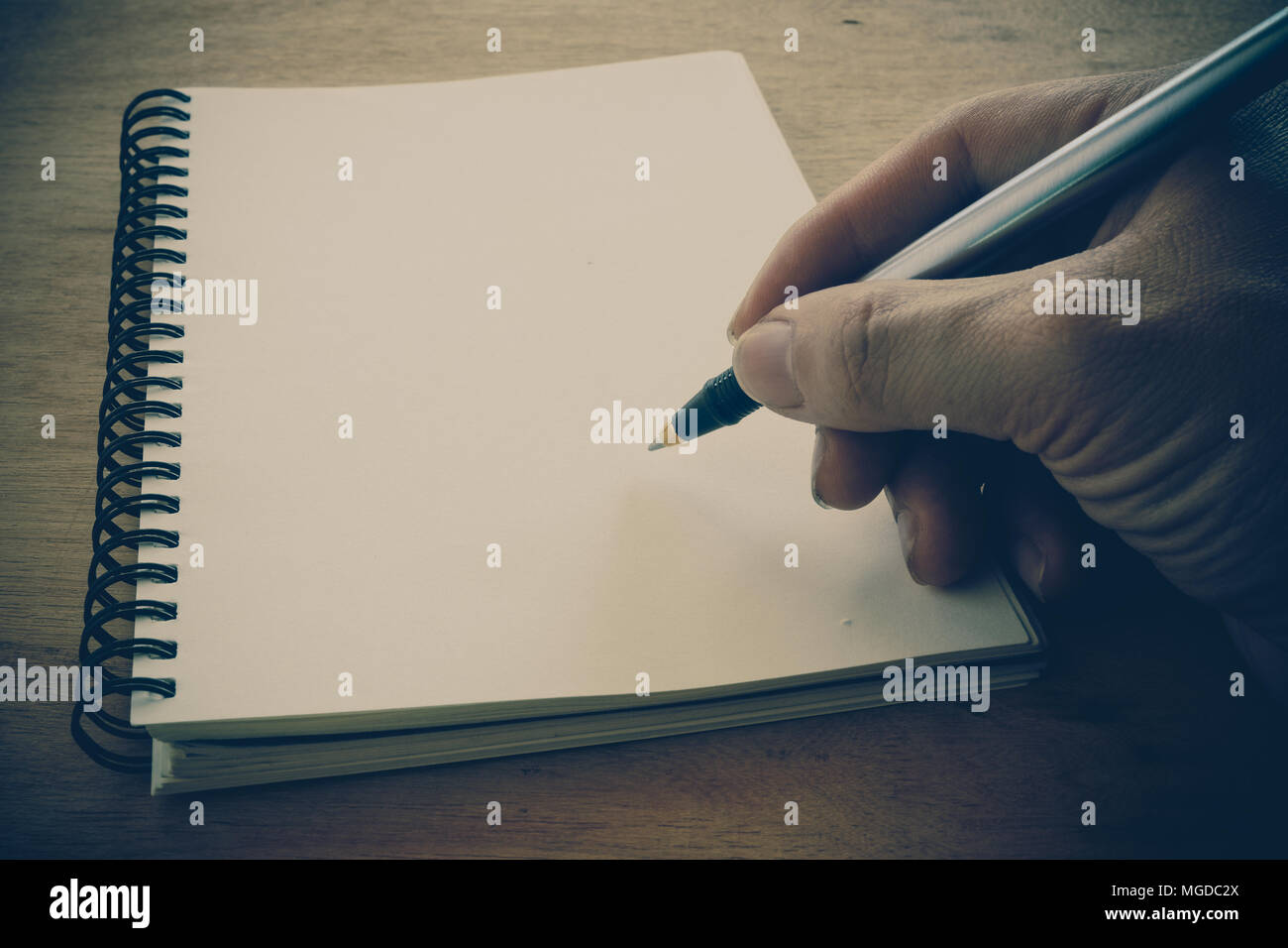 Retro effect faded and toned image of a writing a note with a fountain