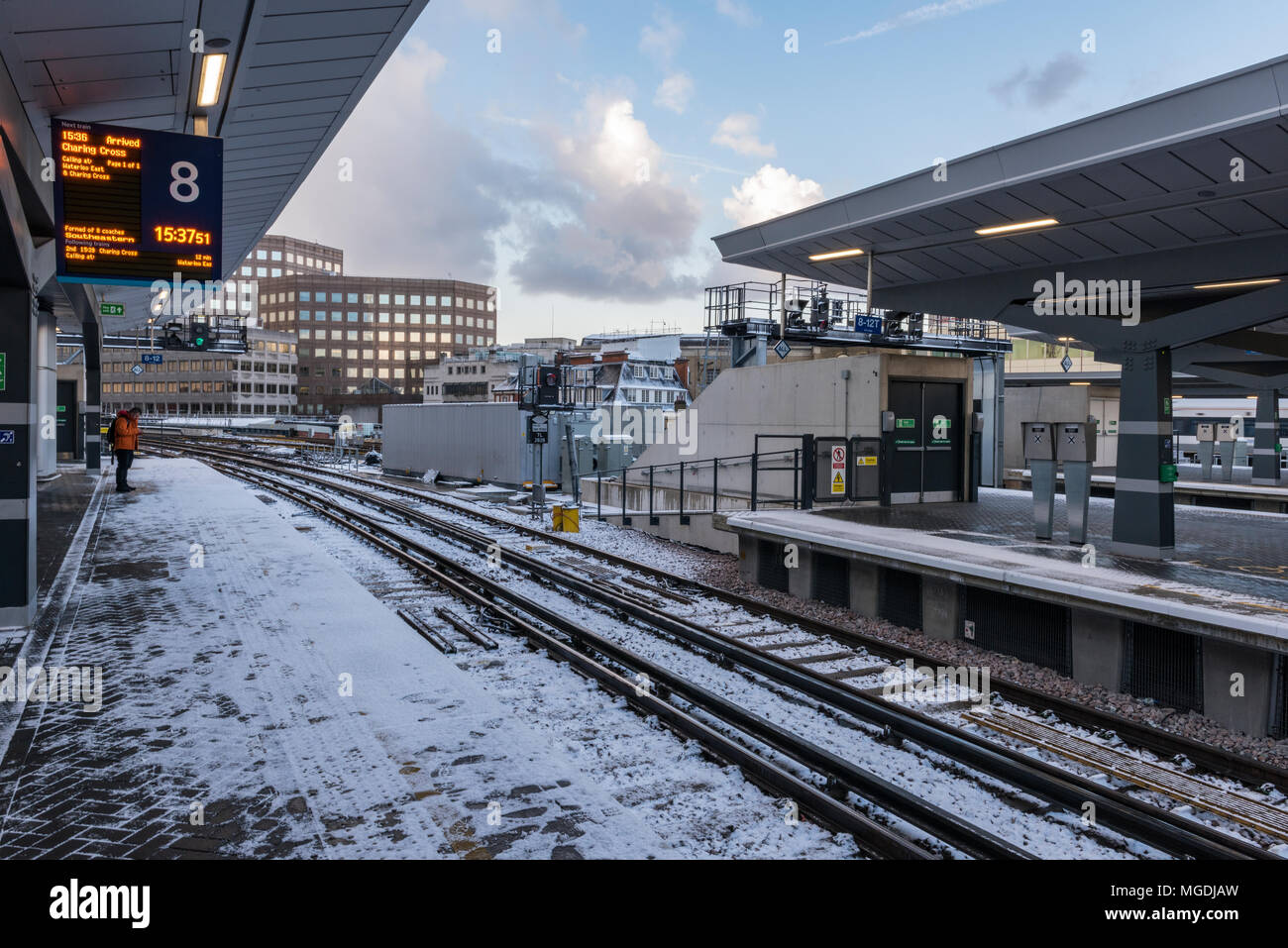 a solitary person stands alone on a platform at the new london bridge railway station in the freezing snow in mid winter. waiting for a train in snow. Stock Photo