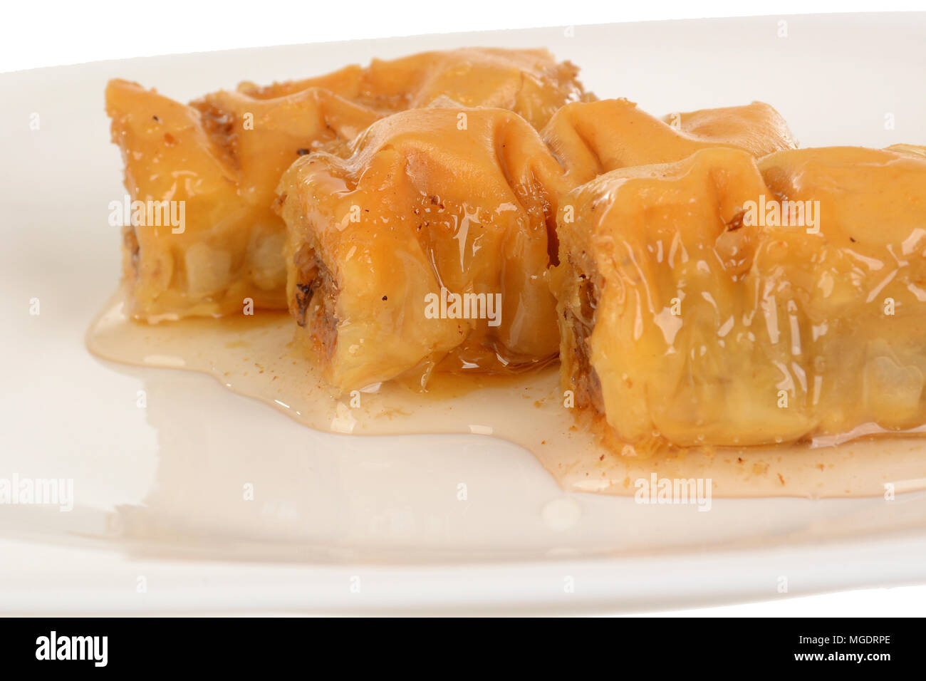 Three pieces of sweet dessert roll baklava in sugary syrup, isolated on white background Stock Photo