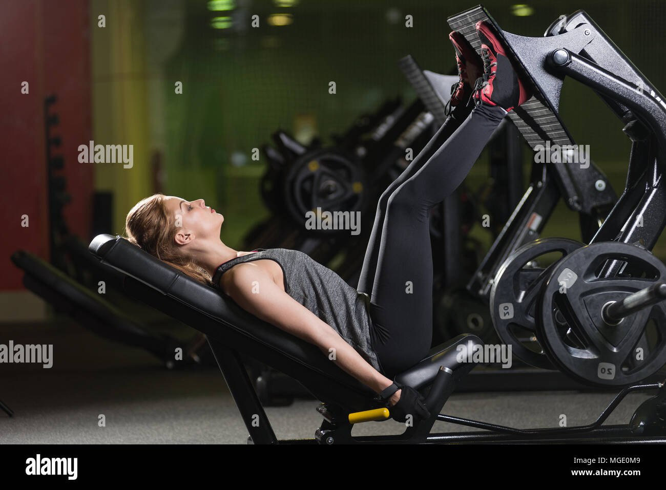 Sportive woman using weights press machine for legs. Gym Stock Photo