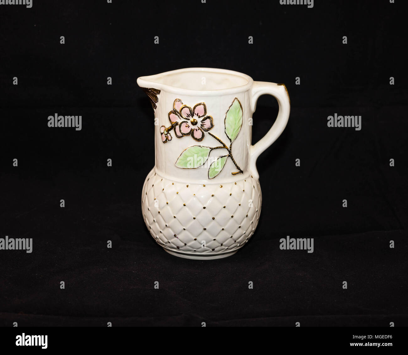 a handmade white pitcher with flowers and gold trim Stock Photo