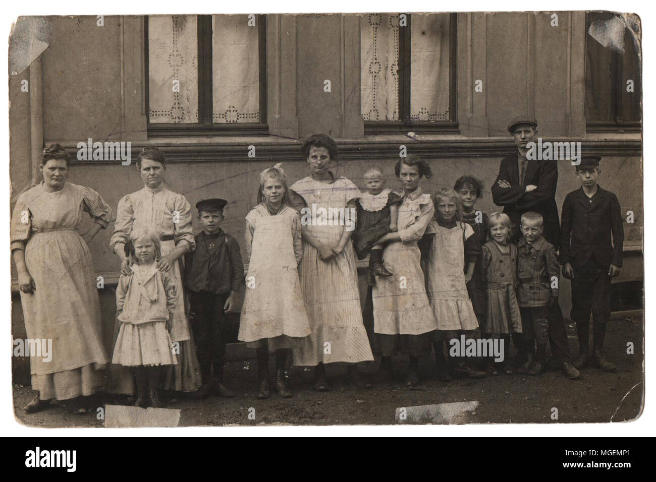 Old family photo in black and white Parents with eleven children in front of a house. Old family photo around 1885, black and white shot in retro styl Stock Photo