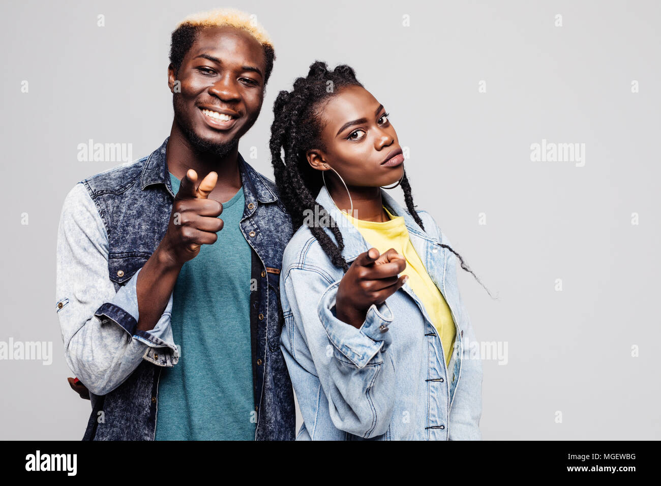 Portrait of a smiling young afro american couple standing and pointing ...