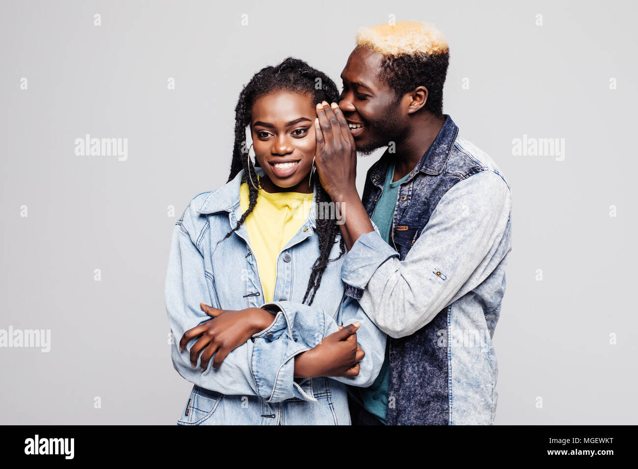 Portrait of a surprised young afro american couple telling secrets ...