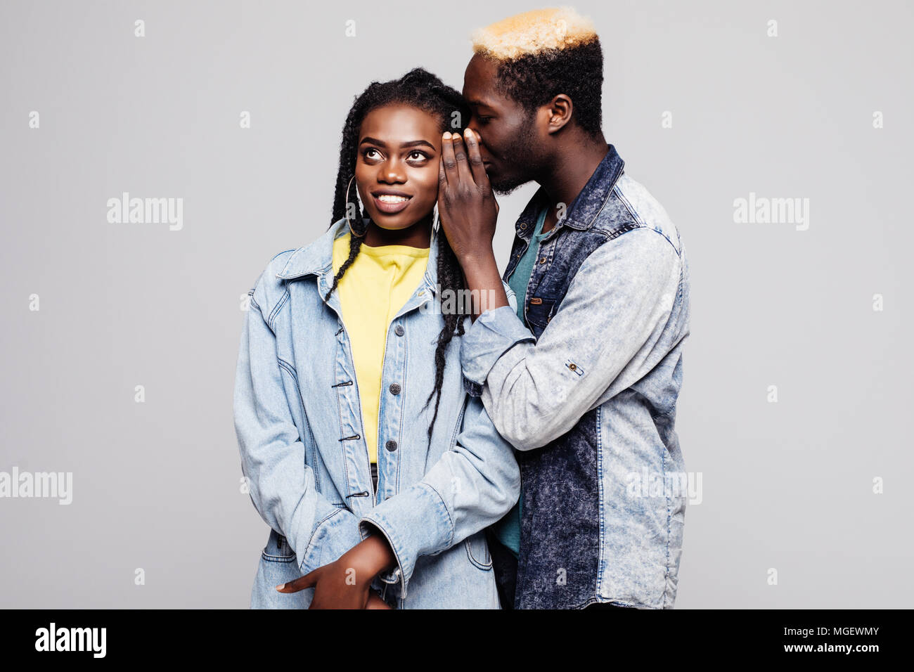Portrait of a surprised young afro american couple telling secrets ...