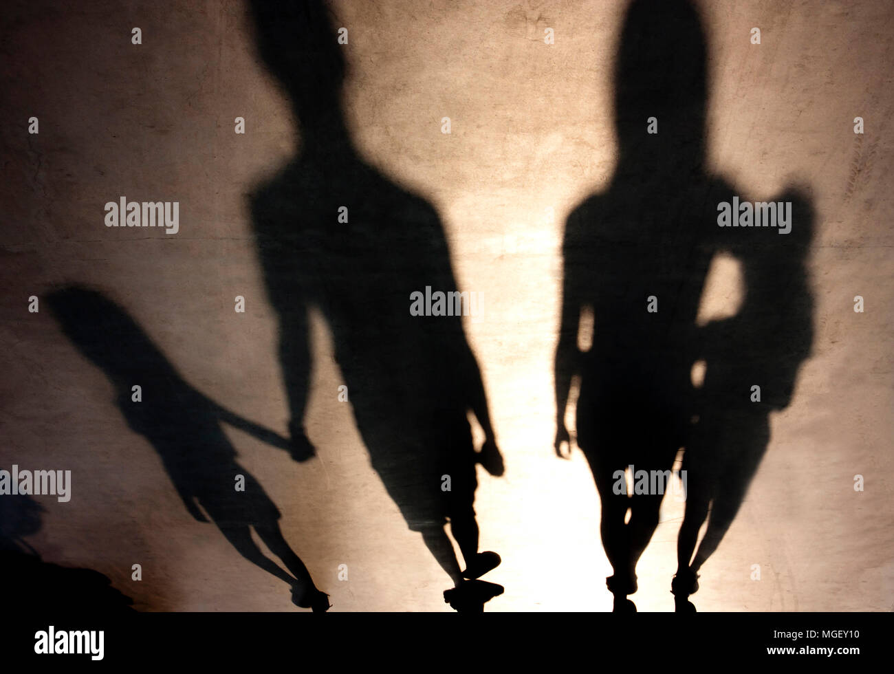 Blurry shadows silhouetes of family with children walking  hand in hand and in a hug in summer sunset Stock Photo