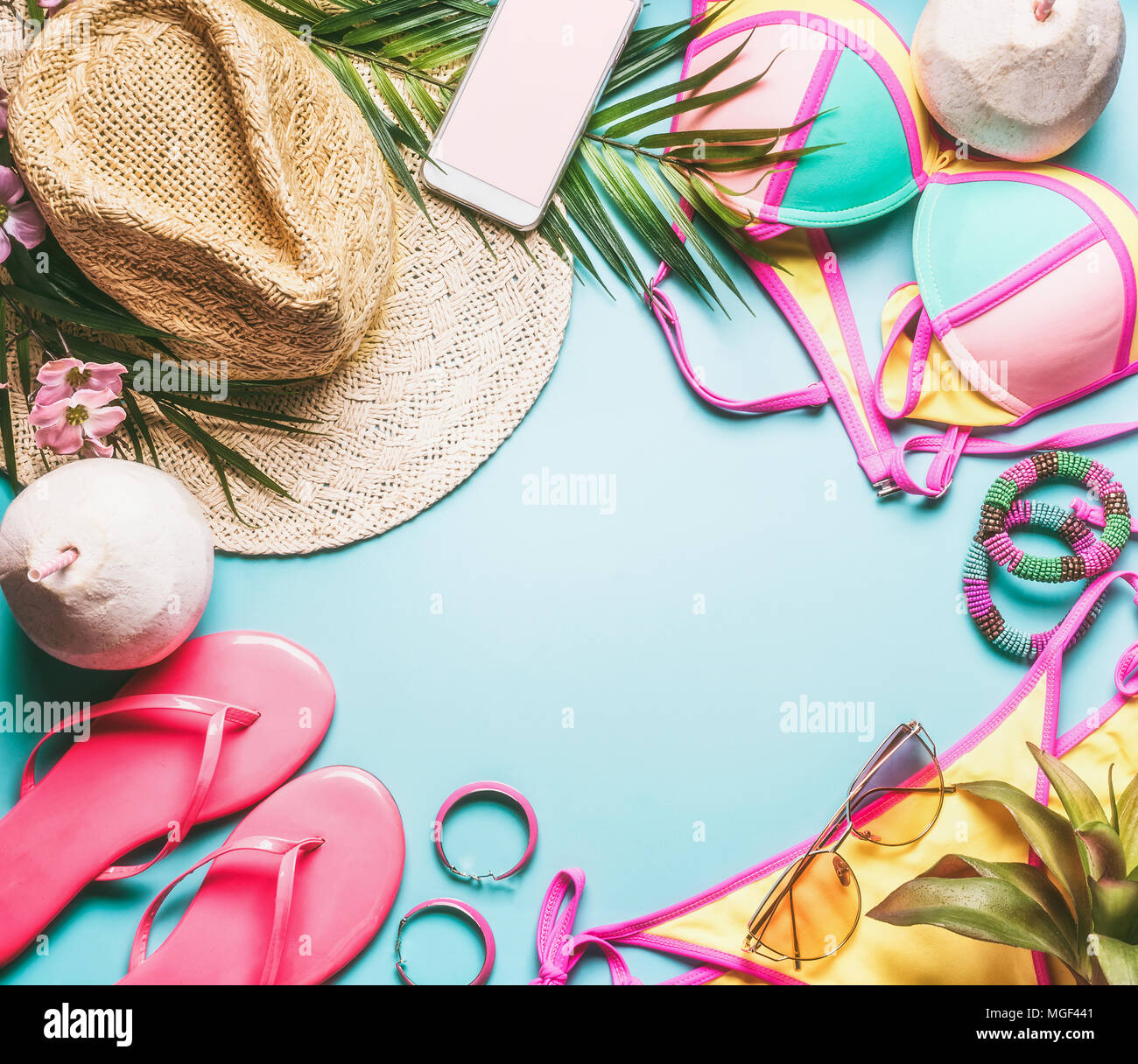 Summer holiday frame. Beach accessories : straw hat, palm leaves, sun glasses, pink  flip flops , bikini and coconut cocktail on blue turquoise backgr Stock Photo