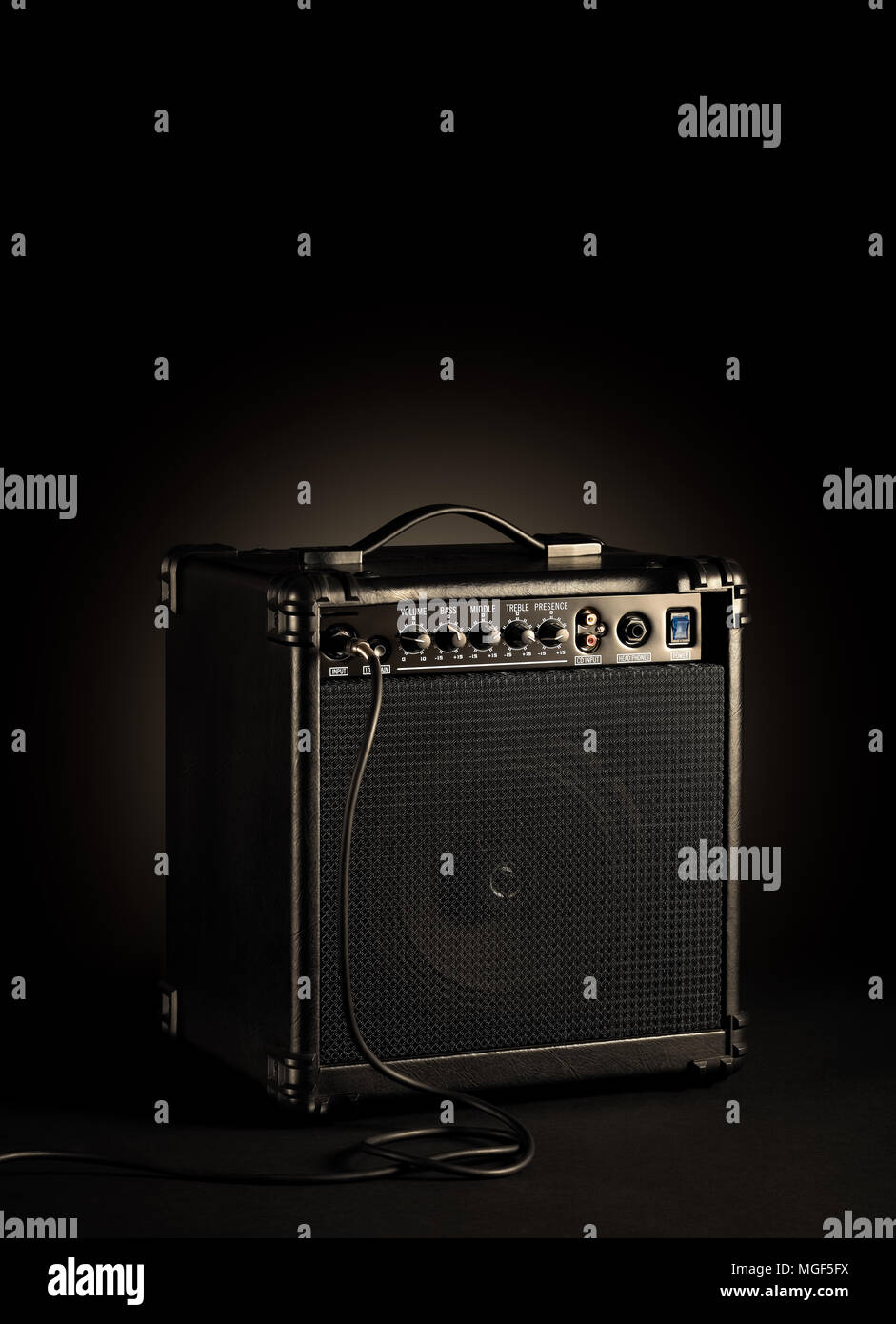 Black bass guitar amplifier whit a cord plugged in on black background