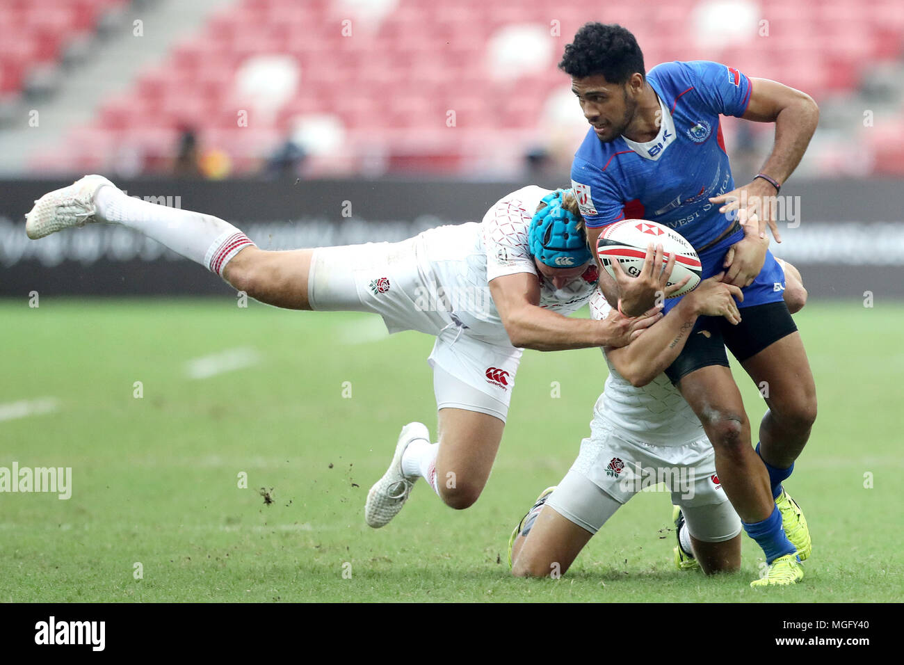 Singapore. 29th Apr, 2018. Elisapeta Alofipo (right) of Samoa is tackled by Richard de Carpentier (left) and Dan Bibby of England during the Cup Quarter Final match between England and Samoa at the Rugby Sevens tournament at the National Stadium. Singapore. Credit: Paul Miller/ZUMA Wire/Alamy Live News Stock Photo