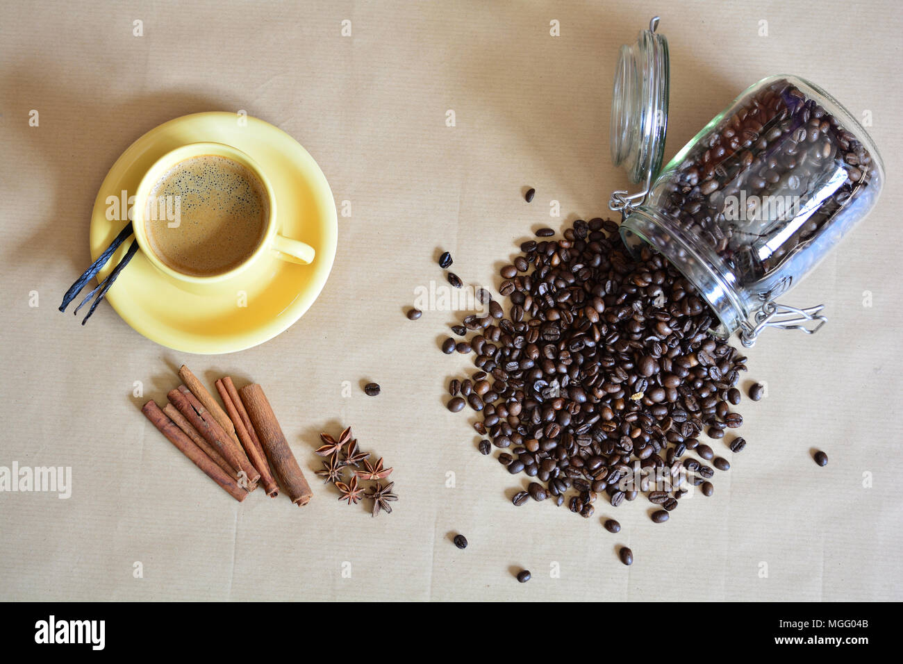 Spilled coffee beans with a cup of coffee and anise, vanilla, cinnamon sticks Stock Photo