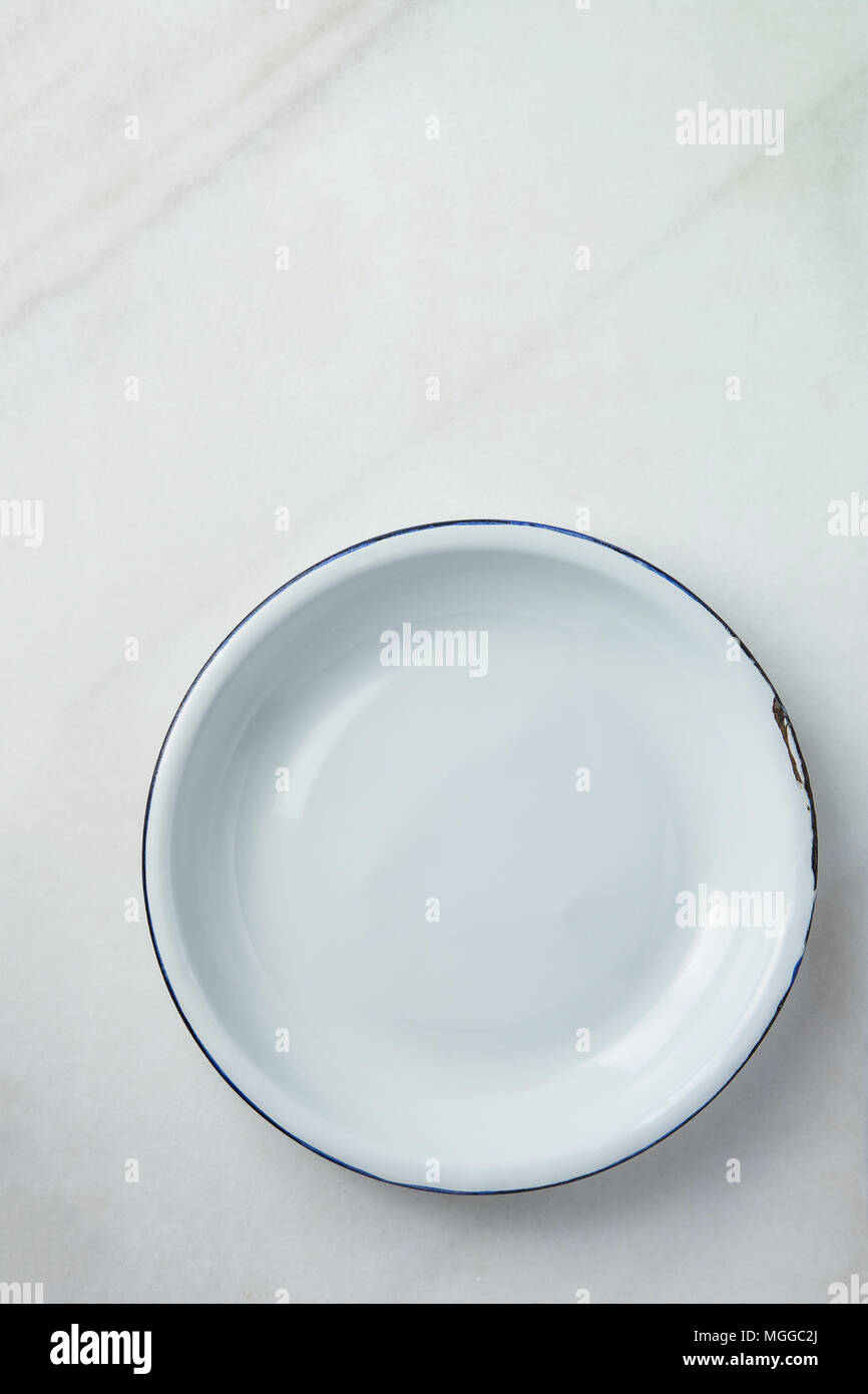 White Vintage Enamel Plate with Blue Edges on Marble Stone Background. Minimalist Style. Template for Poster Banner Cooking Baking Workshop Course. Ea Stock Photo