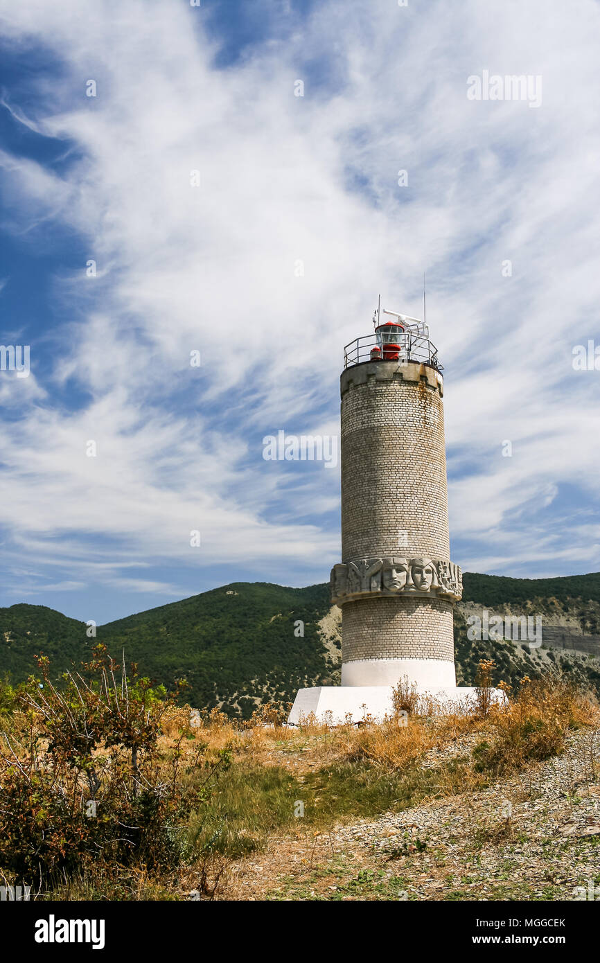 Lighthouse on the Peninsula Bolshoy Utrish, Krasnodarskiy Region, Russia against the Caucasus mountains and summer sky. Stock Photo